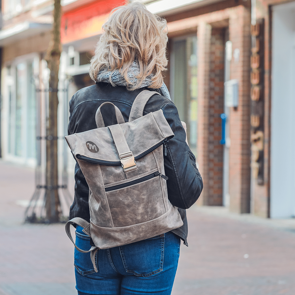 Person trägt den Leder-Rucksack in beige auf der Schulter.