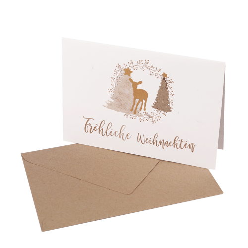 Handgefertigte Klappkarte mit aufgeklebten Tannenbäumen und einem Reh aus Papier und dem Spruch Fröhliche Weihnachten, mit braunem Umschlag.