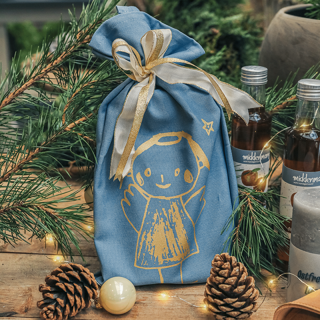 Geschirrtuch in blaugrau mit einem goldenen Engel bedruckt und als Geschenk zusammengebunden.