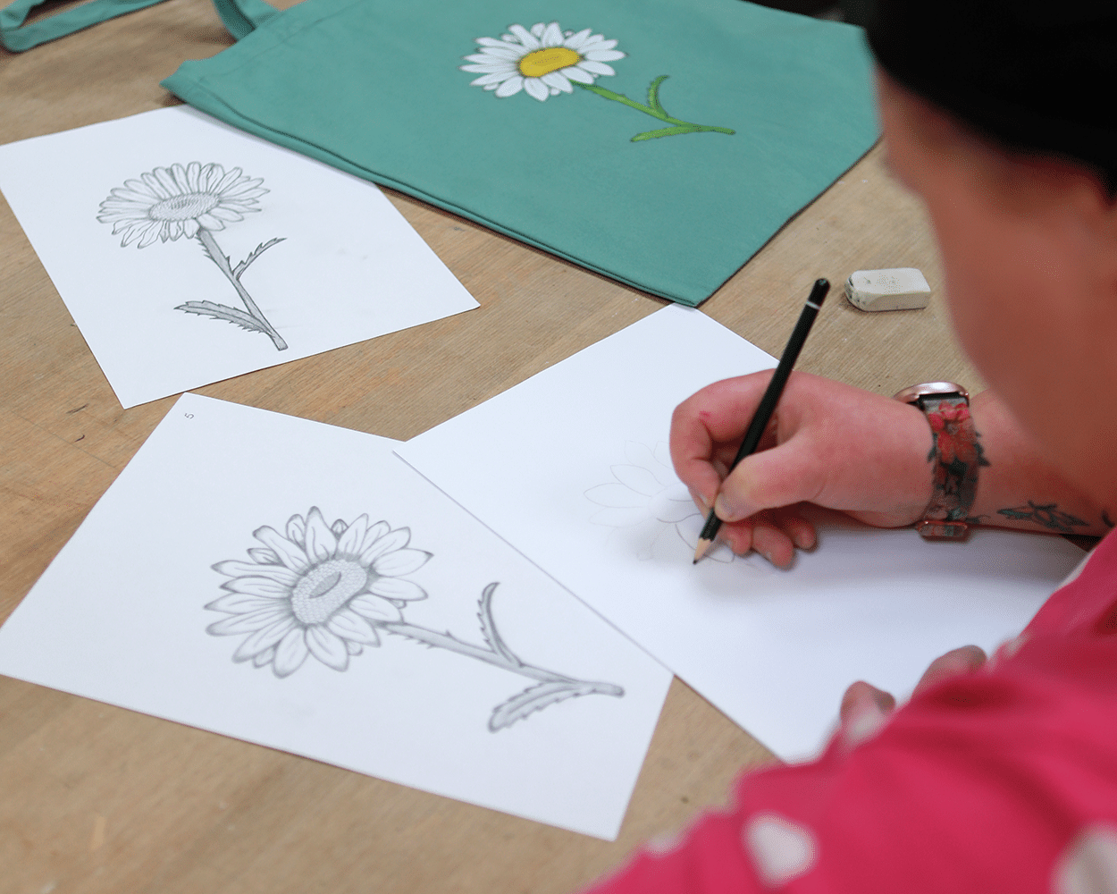 Eine Person zeichnet Gänseblümchen mit dem Bleistift.