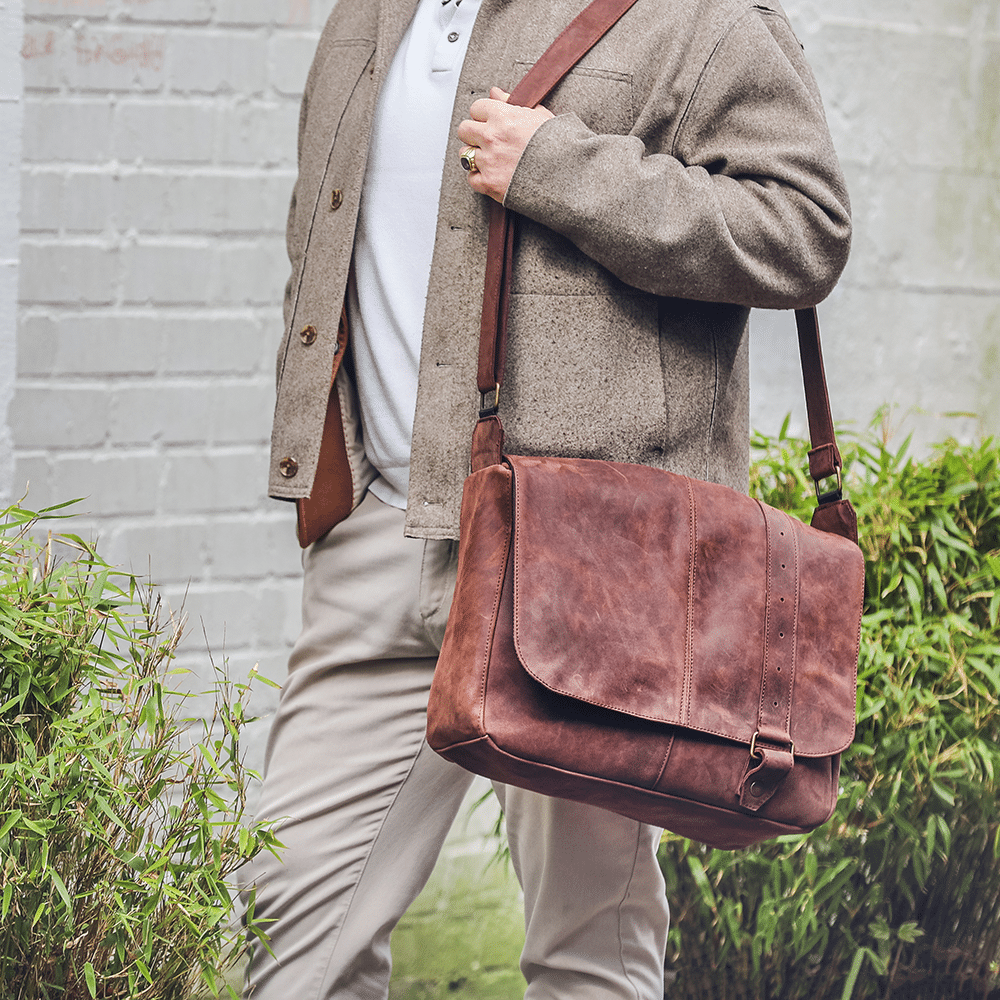 Leder-Umhängetasche in braun wird auf der Schulter getragen.