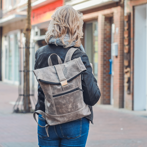 Person tr&auml;gt den Leder-Rucksack in beige auf der Schulter.
