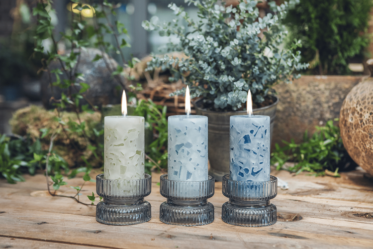 Drei Rundkerzen in Blautönen mit der Aufschrift Ostfreesen Lücht stehen auf Tisch mit Deko.