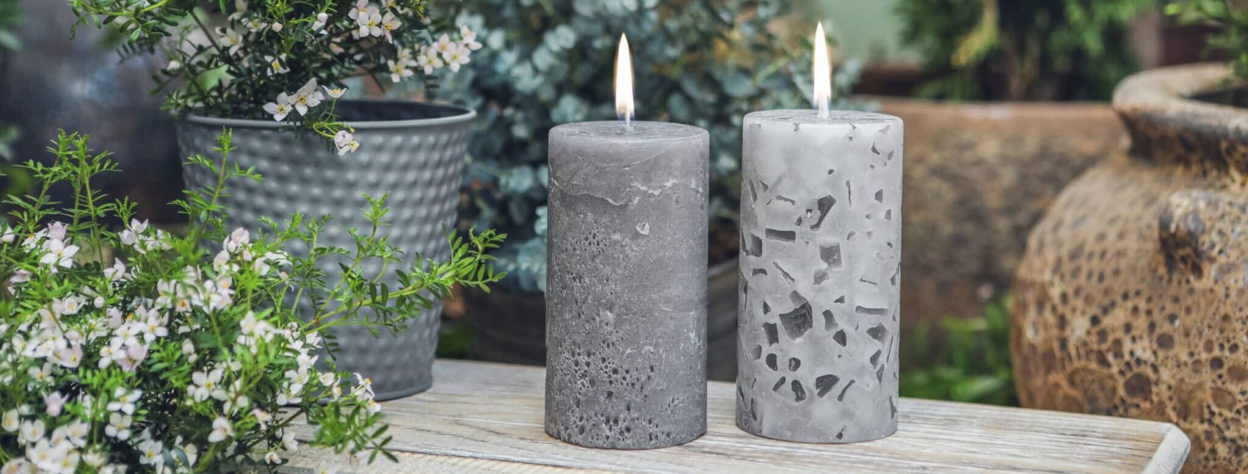 Fünf Stumpenkerzen in den Farben Bubblegum und Avocado, auf einem Holztisch dekoriert mit einem Tablett und Blumen.