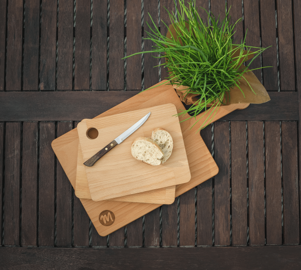 Ein Servierbrett und zwei Brotbretter dekoriert mit Messer, Baguette und Kräutertopf.