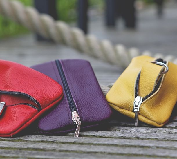 Drei Schlüsseletuis aus Leder in den Farben corallrot, brombeer und curry liegen auf einem Bootssteg.