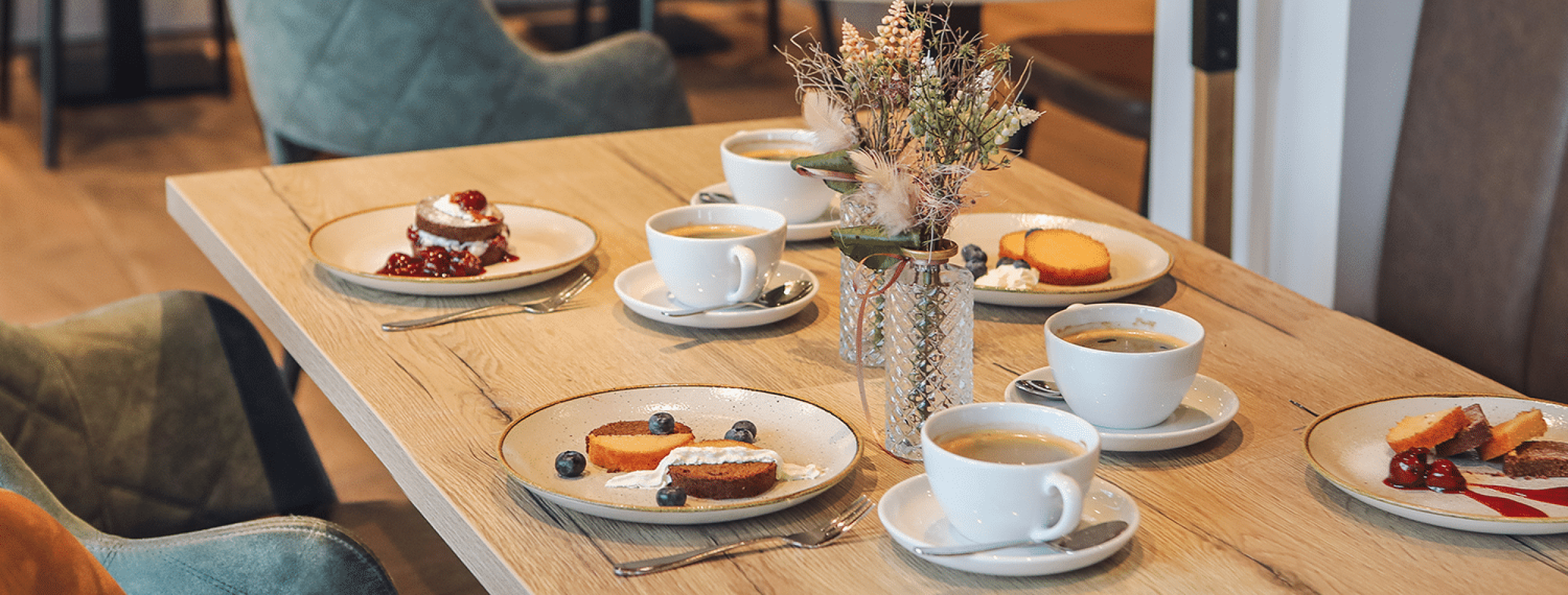 Eine Kaffeetafel, gedeckt mit 4 Sorten Kuchen im Glas und Kaffeetassen.