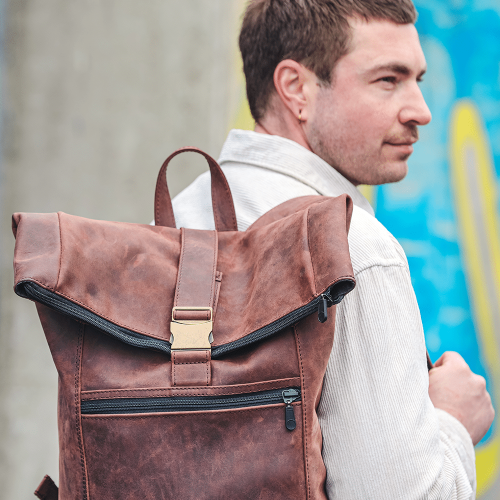 Person tr&auml;gt Leder-Rucksack in braun auf der Schulter.