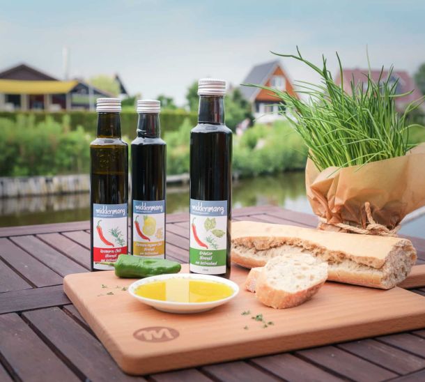 Drei Flaschen Öl, dekoriert an einem Servierbrett.