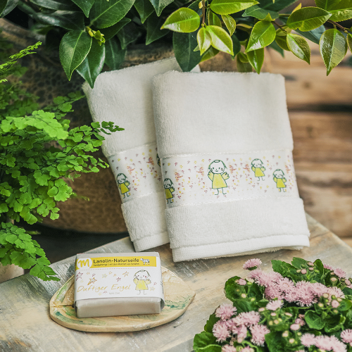 Zwei G&auml;stehandt&uuml;cher auf einem Holztablett, mit Engeln bedruckt und mit einem St&uuml;ck Engelseife daneben.